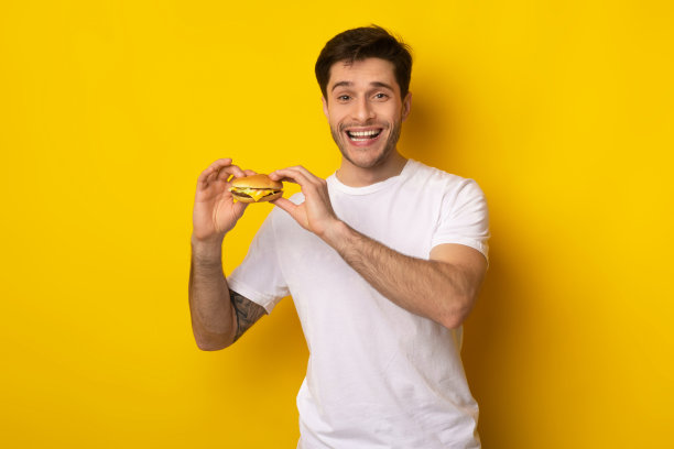 微笑的年轻人拿着汉堡在工作室图片下载