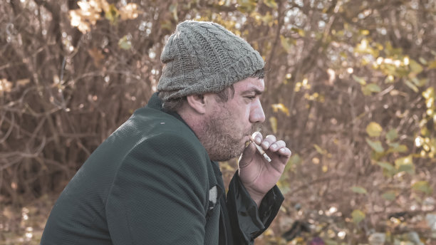 在现代社会，一个手很脏的无家可归的人在抽烟。经济衰退，失业，贫困，饥饿，养老金，全球危机，不平等问题的概念图片下载