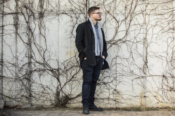 穿着得体的年轻人站在墙前的肖像图片下载