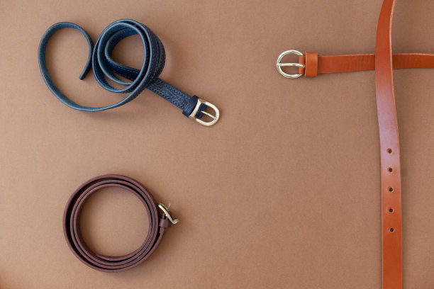 棕色的背景上放着几根手工制作的真皮女士腰带。俯视图，平面与文本空间图片下载
