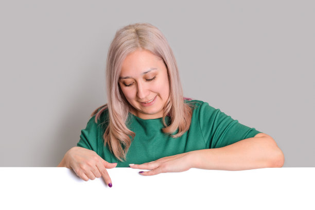 一个中年金发女人用手指着一块空板。图片下载