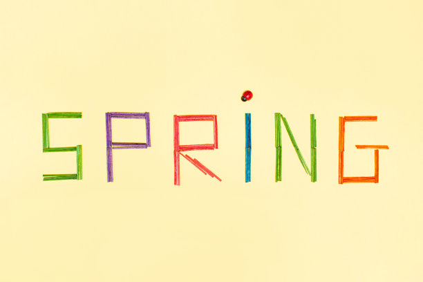 春天的字母在明黄色的背景上点缀着瓢虫，五彩缤纷的字母。春天来了，最小的平铺概念。图片下载