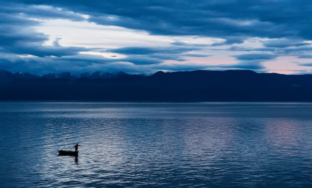 美丽的日落在海上或湖泊与渔船和神秘的反射水面。图片下载