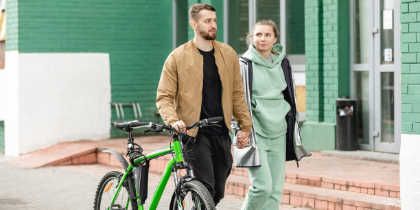 户外的年轻夫妇的肖像。人们在街上骑着绿色的运动山地自行车。男人和女人在一起是幸福和微笑的。生活方式的概念。图片下载