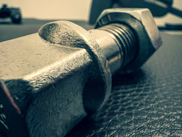 一种用灰色皮革制成的带螺母的大的、用过的螺丝。图片下载