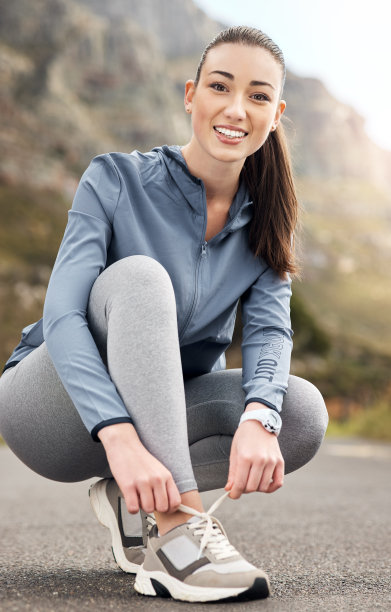 一个女人在路上跑步时系鞋带的照片图片下载