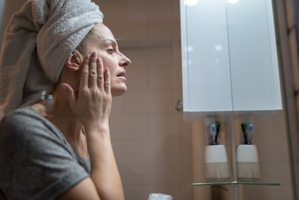 年轻女子淋浴后在脸上涂保湿霜图片下载