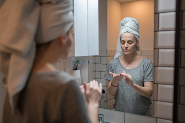 年轻女子淋浴后在脸上涂保湿霜图片下载