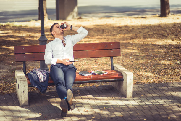 年轻的商人坐在长凳上喝咖啡图片下载