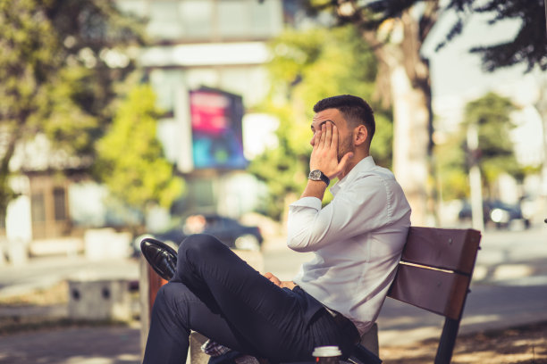 一个白人商人，在公园里看起来很累图片下载