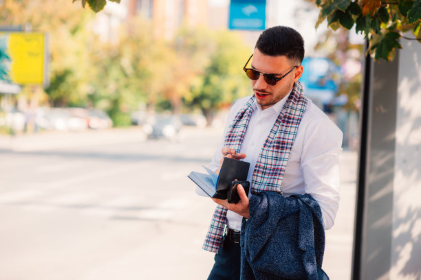 英俊的商人在城市里，手里拿着笔记本，边说边走在街上。图片下载