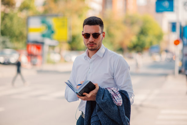 一位穿着白衬衫的现代年轻商人正严肃地站在城市里看书。图片下载