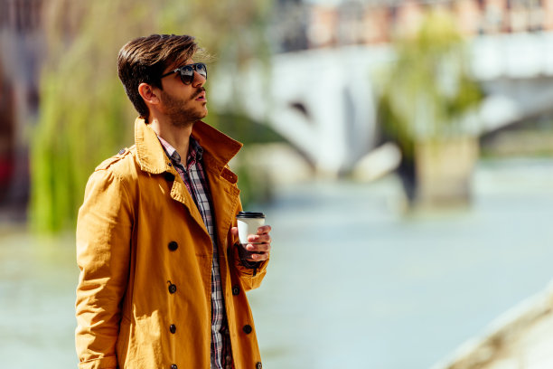 英俊的商人一边喝咖啡一边在河边放松图片下载