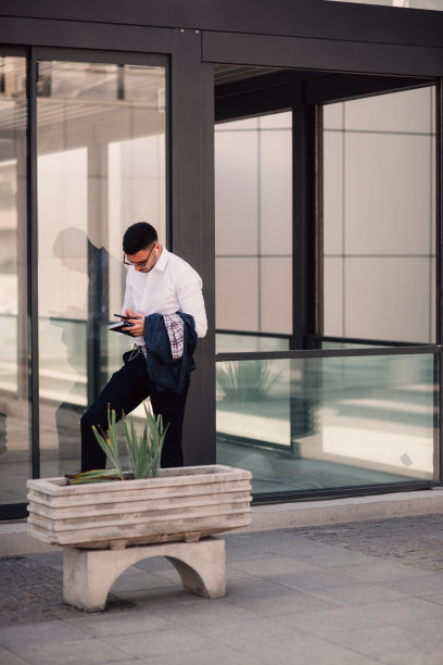 一位城市商人站在市中心美丽的建筑物附近，举着手打电话和争吵。图片下载