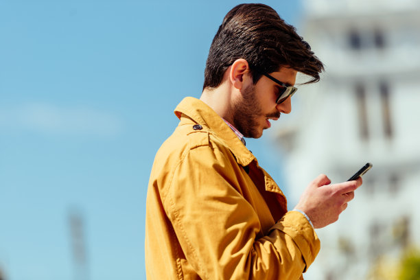 穿着外套的商人在城市里看智能手机图片下载