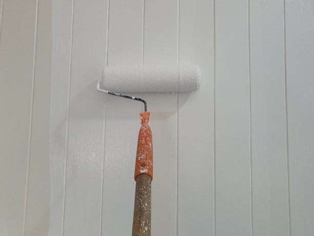 建筑工人用油漆压路机给左墙涂漆图片下载