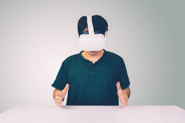 年轻亚洲男子的肖像，戴着眼镜的虚拟现实与兴奋孤立在白色的背景上，元的技术和设备，创新的娱乐和教育与现代。图片下载