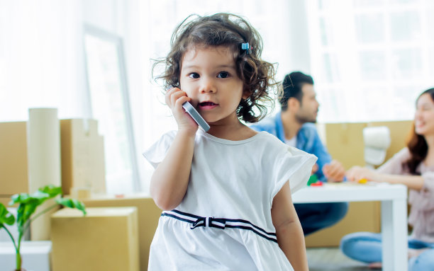 人像小可爱甜甜的白种人女孩与卷曲的头发玩幸福，在室内舒适的房子或公寓与复印空间单独站在电话。教育的概念。图片下载