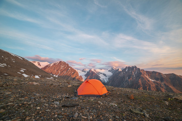令人敬畏的景观，生动的橙色帐篷，在日出的颜色高高的雪山。日出时，金色的岩石和山脉映衬着五彩缤纷的景色。黄金清晨在非常高的海拔。图片下载