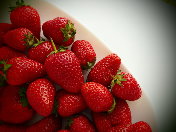 草莓盘，白色背景。白色的盘子和美味的红色大花园草莓。健康的食物，维他命和素食。有食物的静物。副本的空间。平躺图片下载
