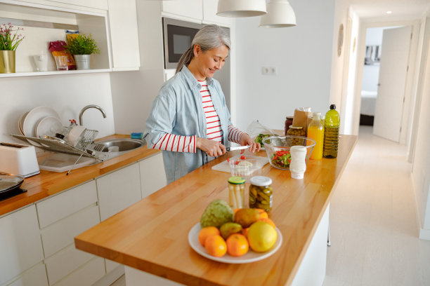 微笑的女人在厨房里准备沙拉的配料图片下载