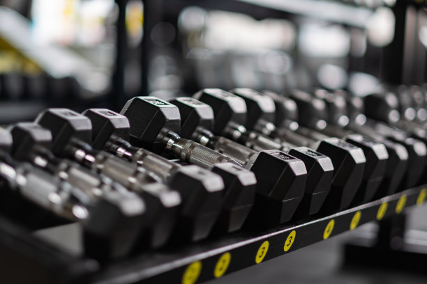 哑铃在健身房排成一排。背景模糊图片下载