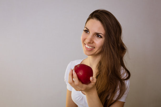 一个年轻女人在厨房里手里拿着一个苹果的肖像图片下载