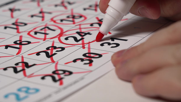 特写手在日历上绘制红色标记数字。图片下载