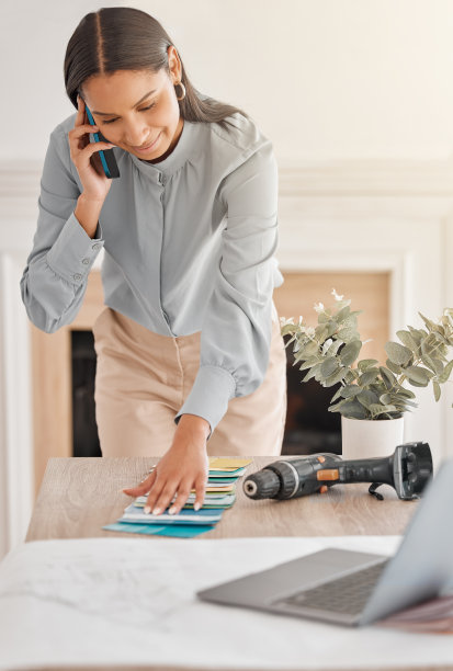 拍摄的年轻女性室内设计看着色板，而在电话图片下载