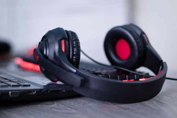 键盘上有红色细节的耳机，还有红色发光按钮。耳机用于玩，工作，听音乐。图片下载