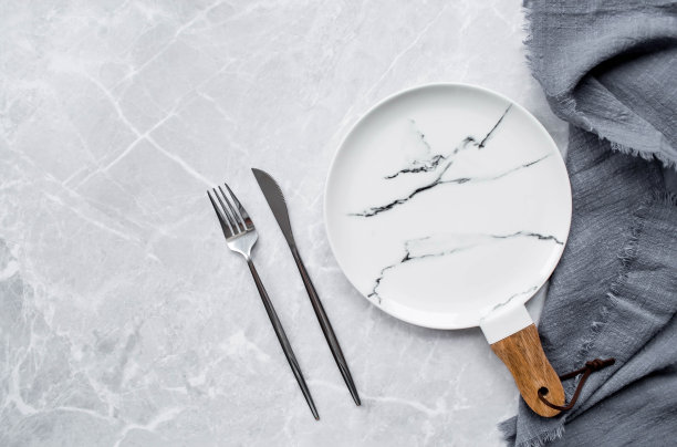 横幅。一个空的陶瓷大理石盘子，木柄，叉子，刀子和毛巾，背景是灰色的混凝土桌子。空间的文本。咖啡馆和餐厅的菜单概念。图片下载