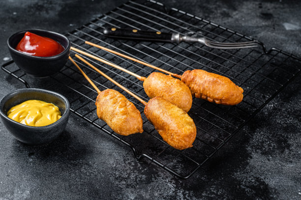 炸玉米热狗配芥末和番茄酱。黑色背景。俯视图图片下载