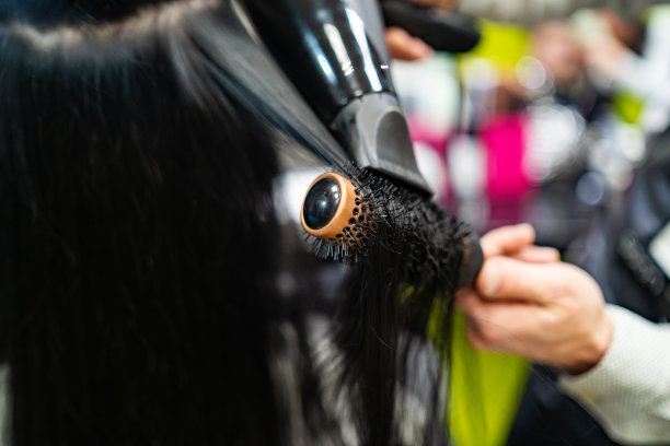 发型师用吹风机和梳子梳理黑色头发图片下载