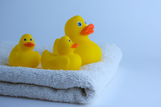 清晨在浴室里，黄色的橡皮小鸭躺在白色的毛巾布上。图片下载