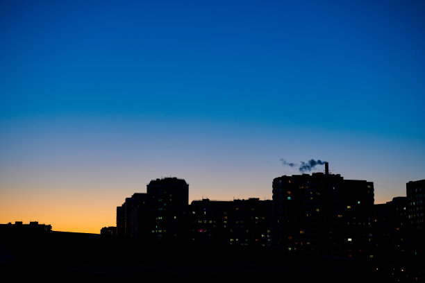 城市建筑的黑色轮廓映衬在晴朗的夜晚深蓝色的天空下。傍晚天空渐黄渐蓝。晚上在城市。夜晚的城市。城市景观背景。图片下载