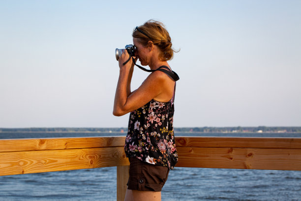 女摄影师在湖边拍照图片下载