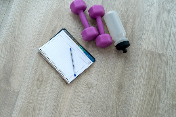 运动器材，哑铃，笔记本，笔在彩色垫子上。图片下载