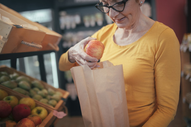 女人用纸袋买水果。图片下载