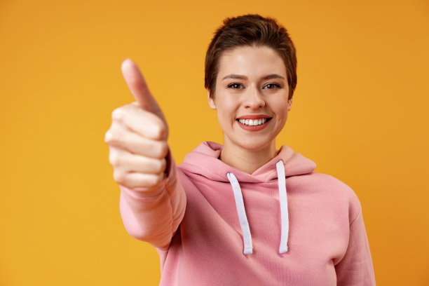 年轻快乐快乐的女人在黄色的背景下竖起大拇指图片下载