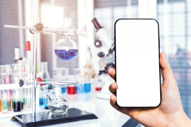 女性使用智能手机模糊图像显微镜和试管与实验室玻璃器皿在实验室背景，研究和科学概念的特写图片下载