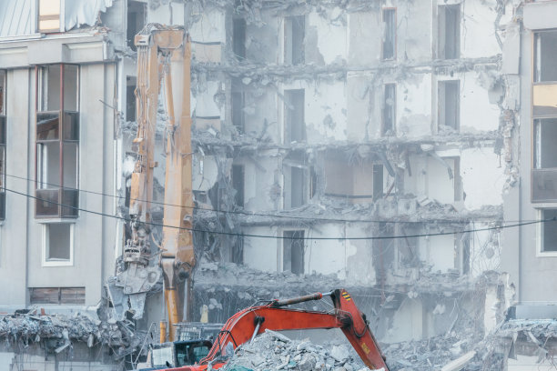 用挖掘机铲斗清理建筑杂物。建筑拆除挖掘机，重型机械，推土机，反铲机图片下载