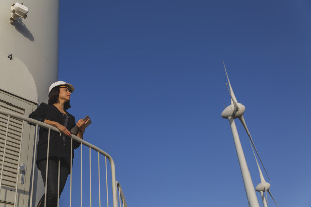 女商人正在用数码平板电脑检查风力涡轮机的可再生能源。图片下载