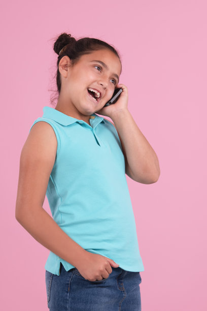 一个小女孩在粉红色的背景下用手机聊天图片下载