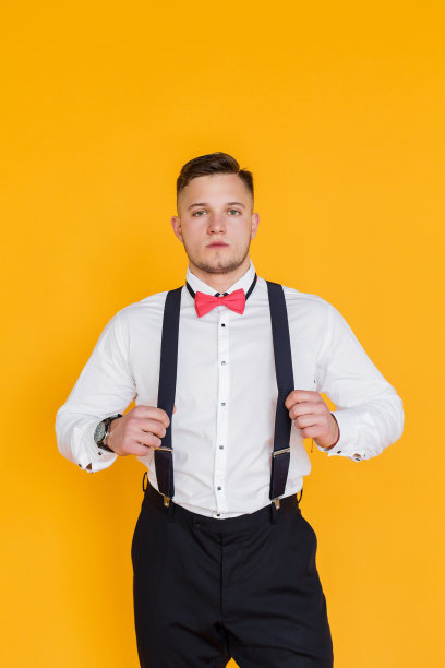 在乌克兰，一幅有吸引力的25岁男子商人的肖像，他拿着黄色背景的背带。图片下载