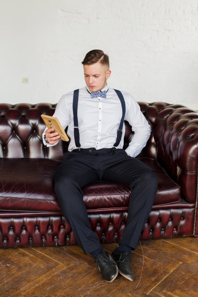 有魅力的年轻人，未来一代商人坐在沙发上看着画像。图片下载