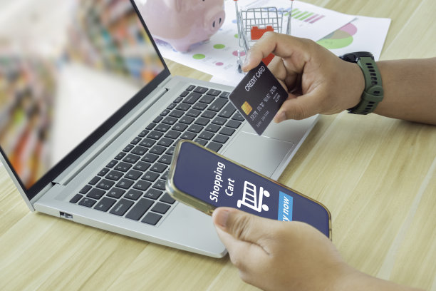 男人的手使用智能手机和笔记本电脑在家里进行网上购物，手握手机与支付详情页面显示和信用卡，网上购物的概念。图片下载