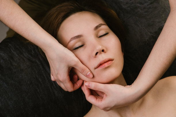 美丽的女人在美容院接受面部按摩图片下载