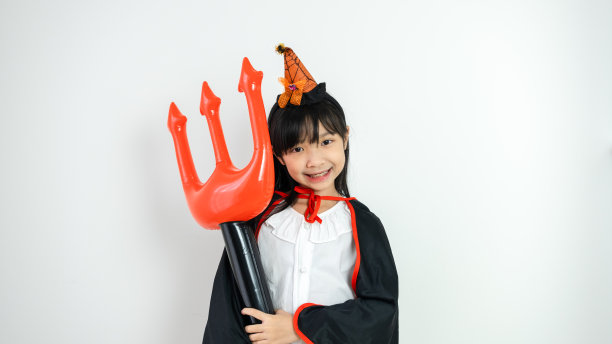 可爱的亚洲女孩微笑着，在白色背景上穿着万圣节主题的女巫服装。图片下载