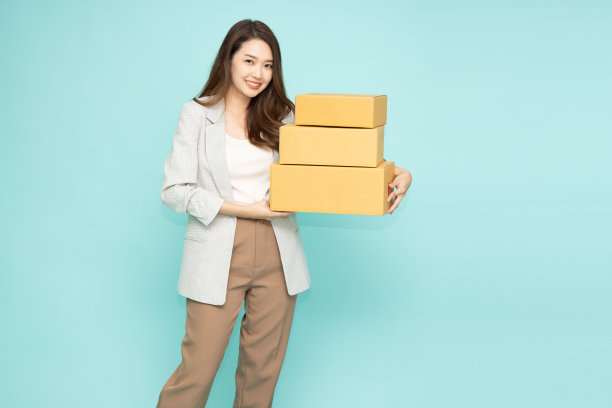 亚洲女人的肖像，拿着包裹包裹盒子孤立在绿色的背景上，快递和航运服务的概念图片下载