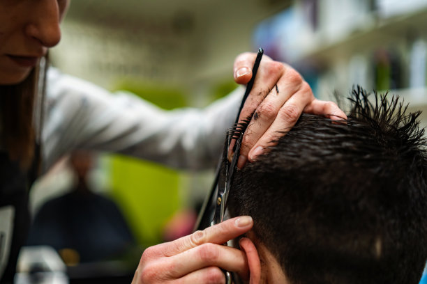 年轻的成年女性发型师使用剪刀和梳子理发图片下载